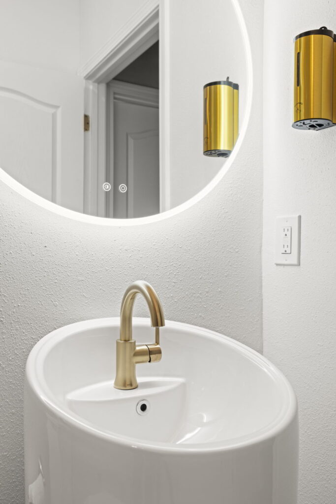Modern bathroom sink with gold faucet and mirror.
