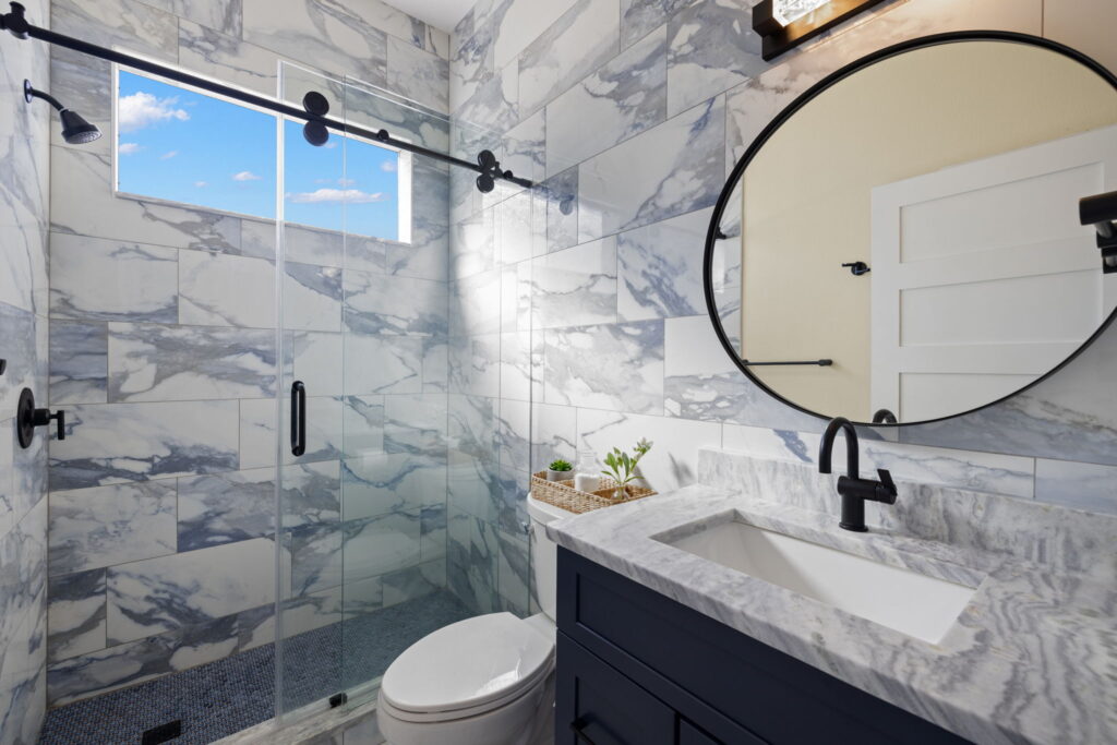 Modern bathroom with marble tiles and glass shower.