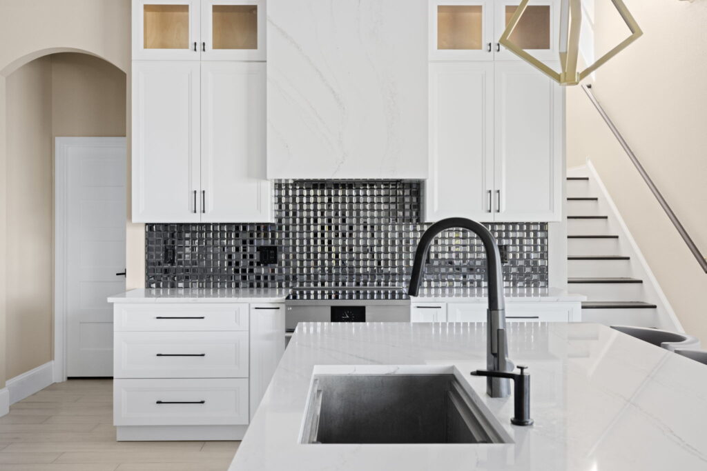 Modern white kitchen with black backsplash and faucet.