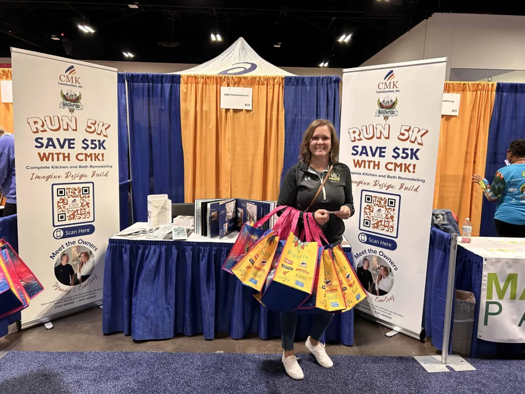 Woman at CMK Construction booth with shopping bags.