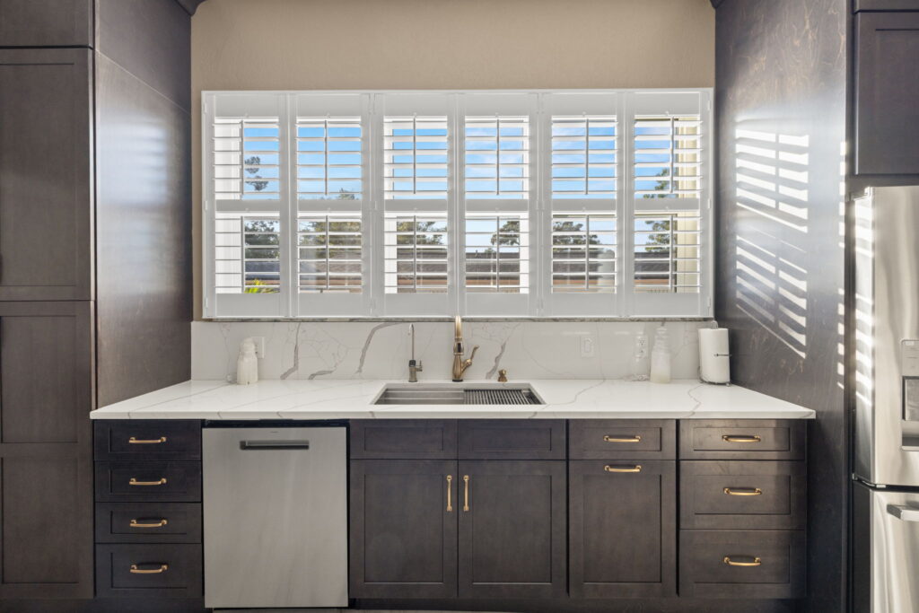 White countertop kitchen with dark cabinets and white shutters