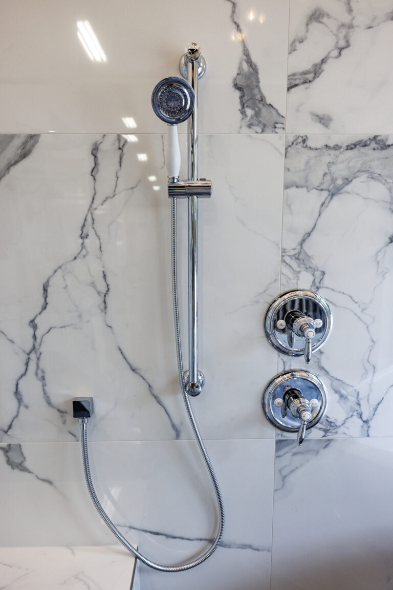 Metallic showerhead on a marble backdrop in a beautiful showroom.