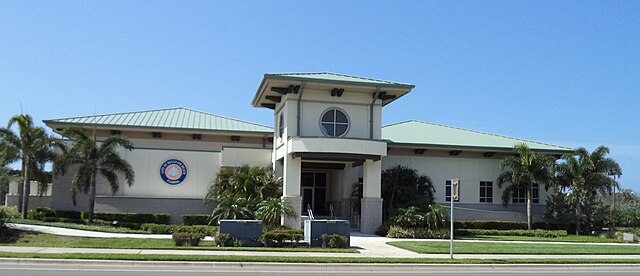 Modern building with palm trees and blue sky.