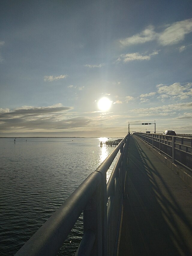 Sunset over a calm pier by the water.