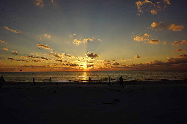 Sunset over ocean with silhouettes of people