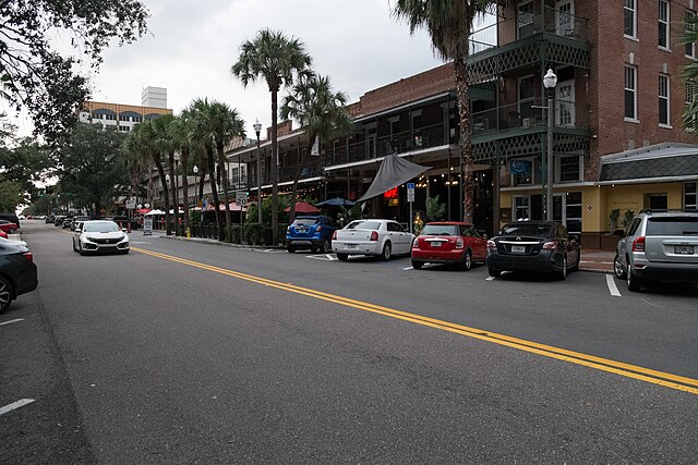 Street lined with restaurants and palm trees.