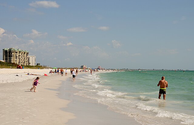 People enjoying a sunny beach day near the water.