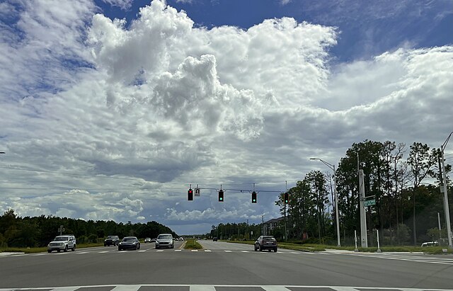 Traffic lights at a busy intersection with clouds