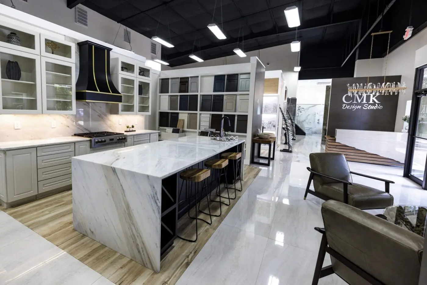 The CMK Design Studio cabinet showroom in Tampa with a marble island, range hood, and cabinet door displays