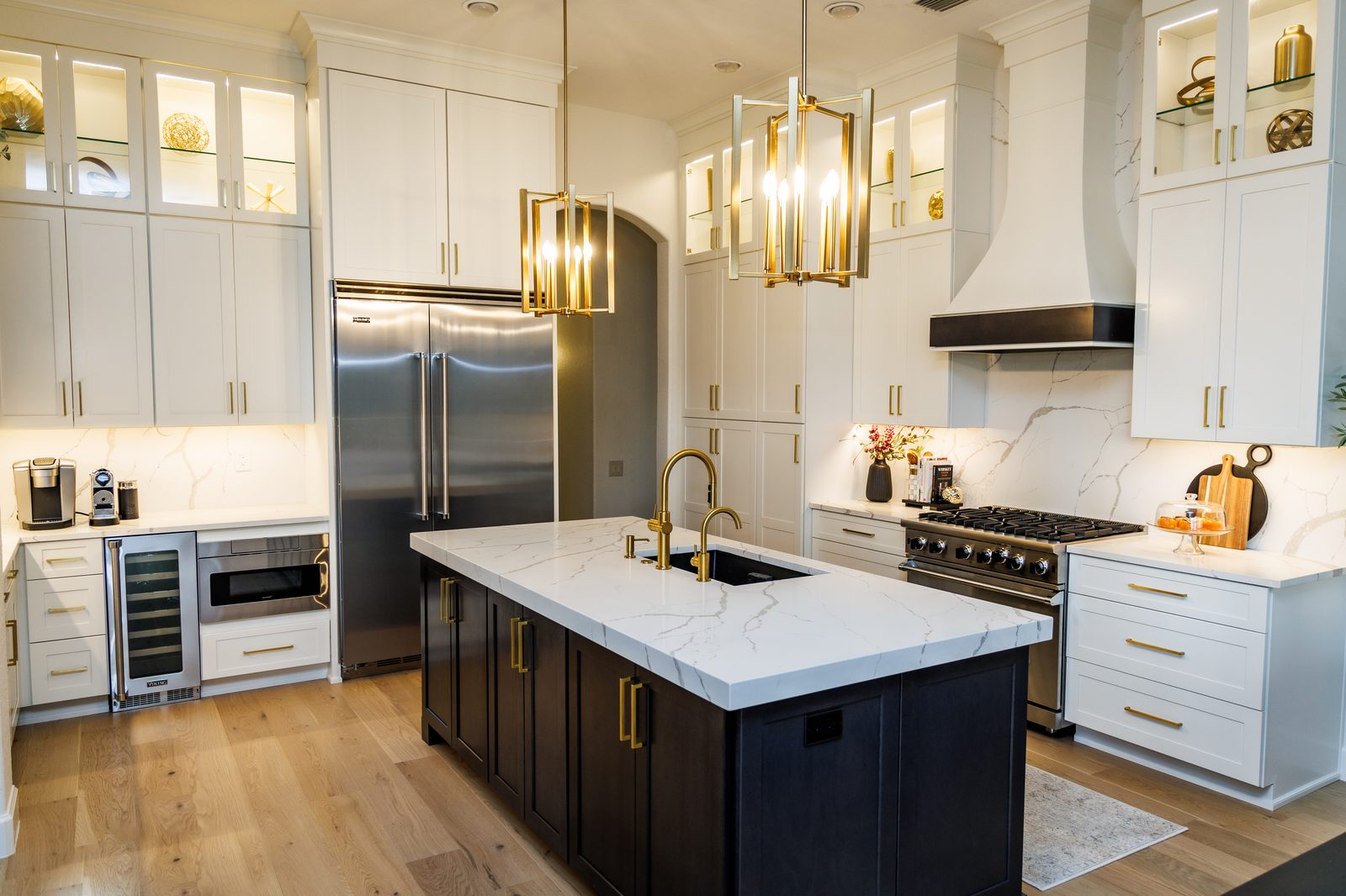 A completed Tampa kitchen project by CMK Construction with new white and navy custom cabinets, quartz counters, and gold hardware