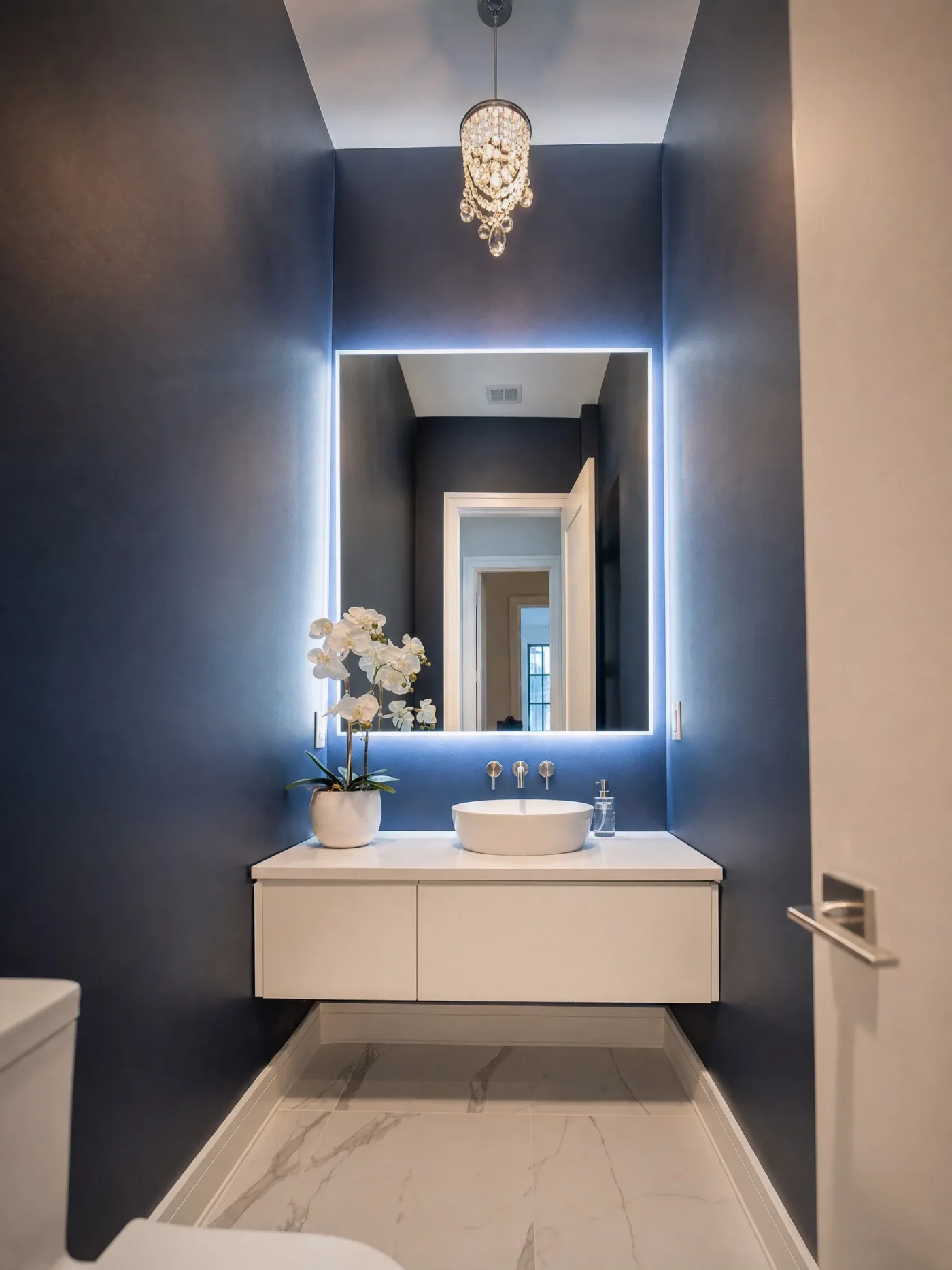 Backlit mirror with floating halo effect above white floating vanity with vessel sink in navy powder room in St Petersburg FL by CMK Construction