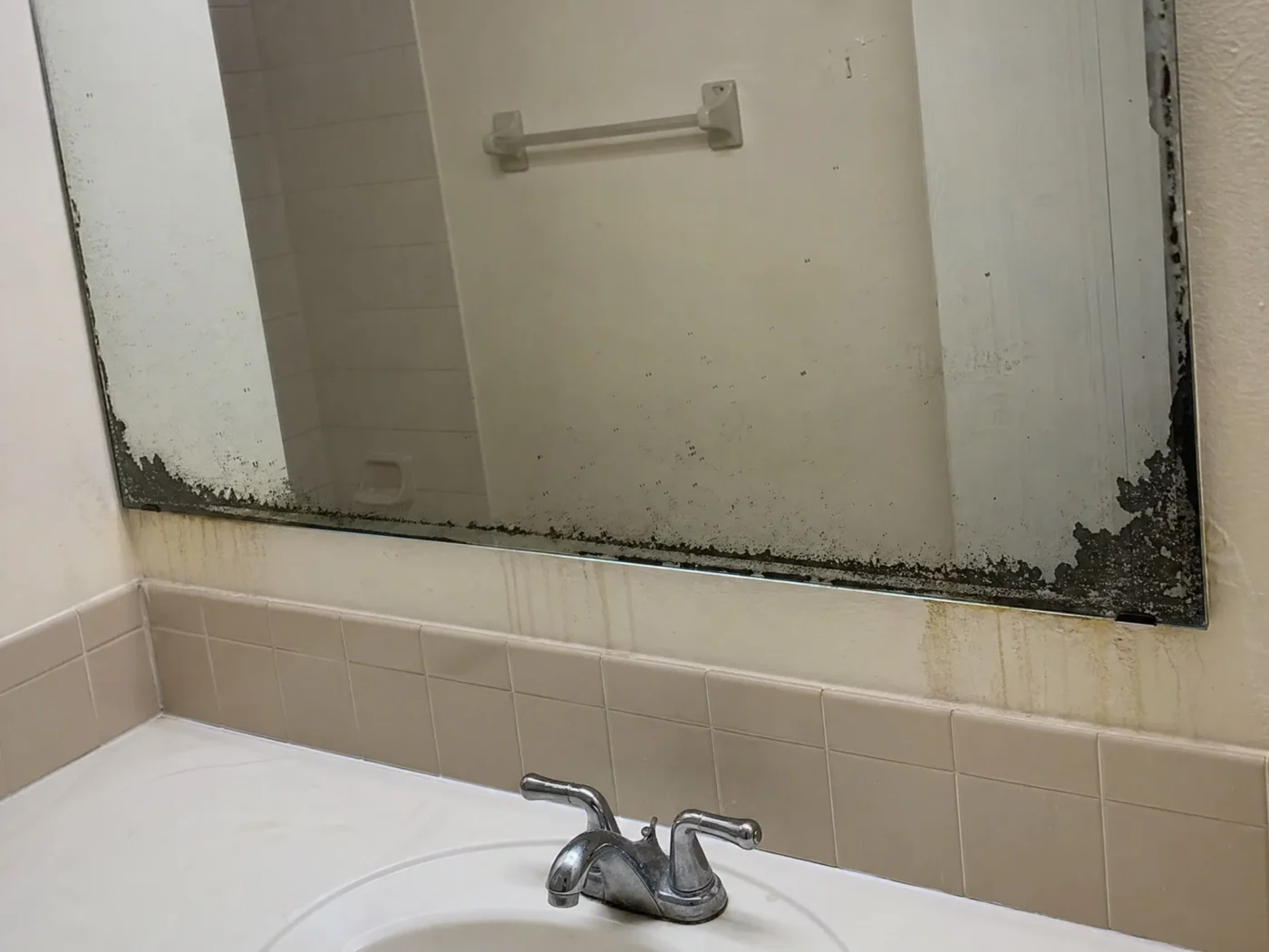 Bathroom mirror showing black edge desilvering and oxidation damage from Florida humidity before replacement by CMK Construction
