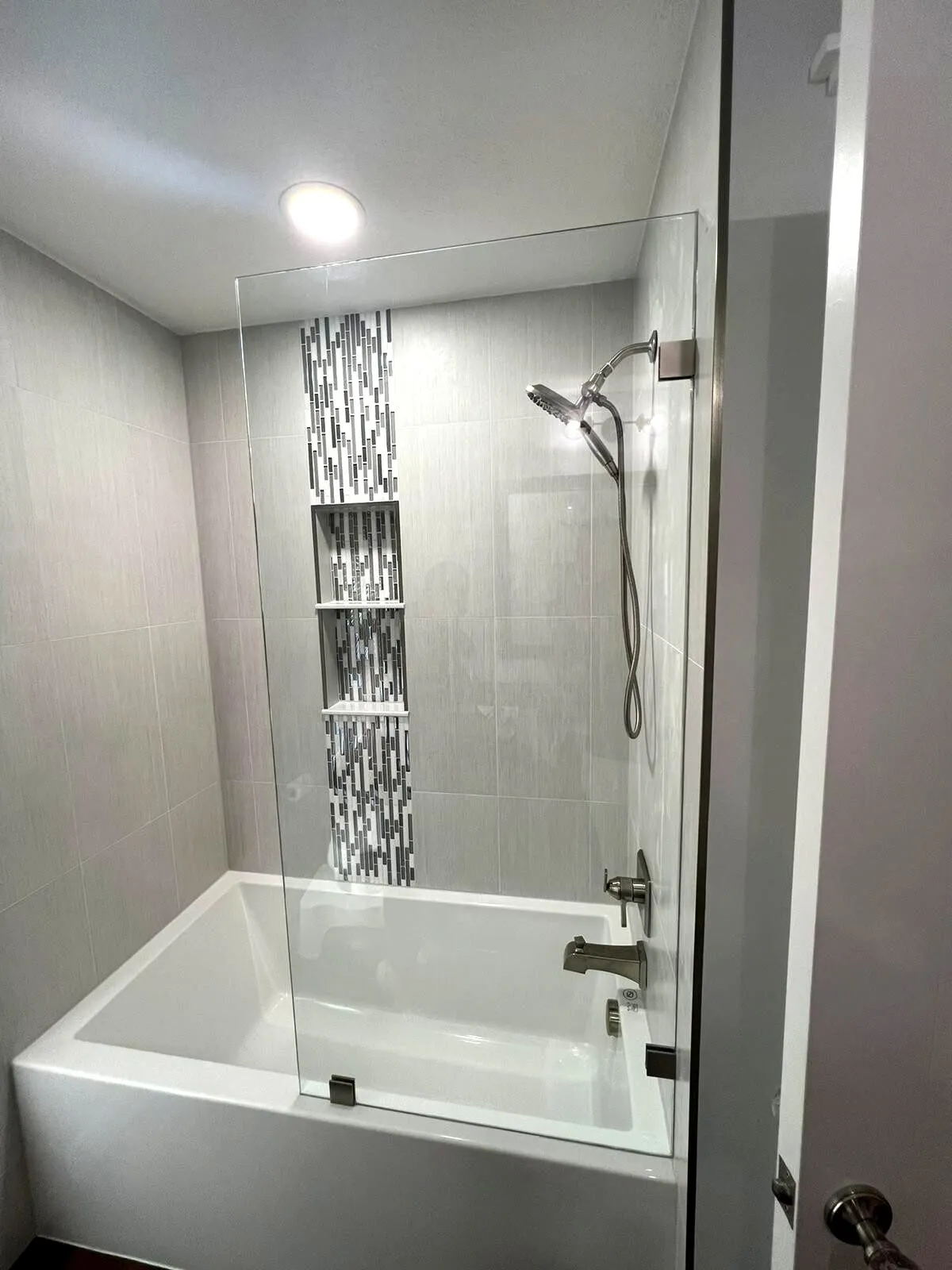Completed bathroom remodel in Safety Harbor FL by CMK Construction with gray large format tile, glass mosaic accent, and triple shower niche