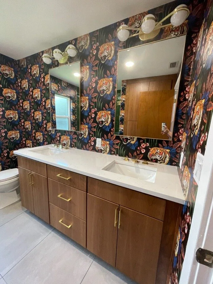 Walnut double vanity with white quartz top, brass hardware, and bold tiger wallpaper after remodeling in Siesta Key by CMK