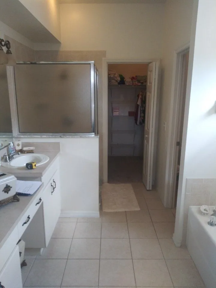 Dated builder grade primary bathroom before remodeling in Land O Lakes with framed glass shower and cultured marble vanity