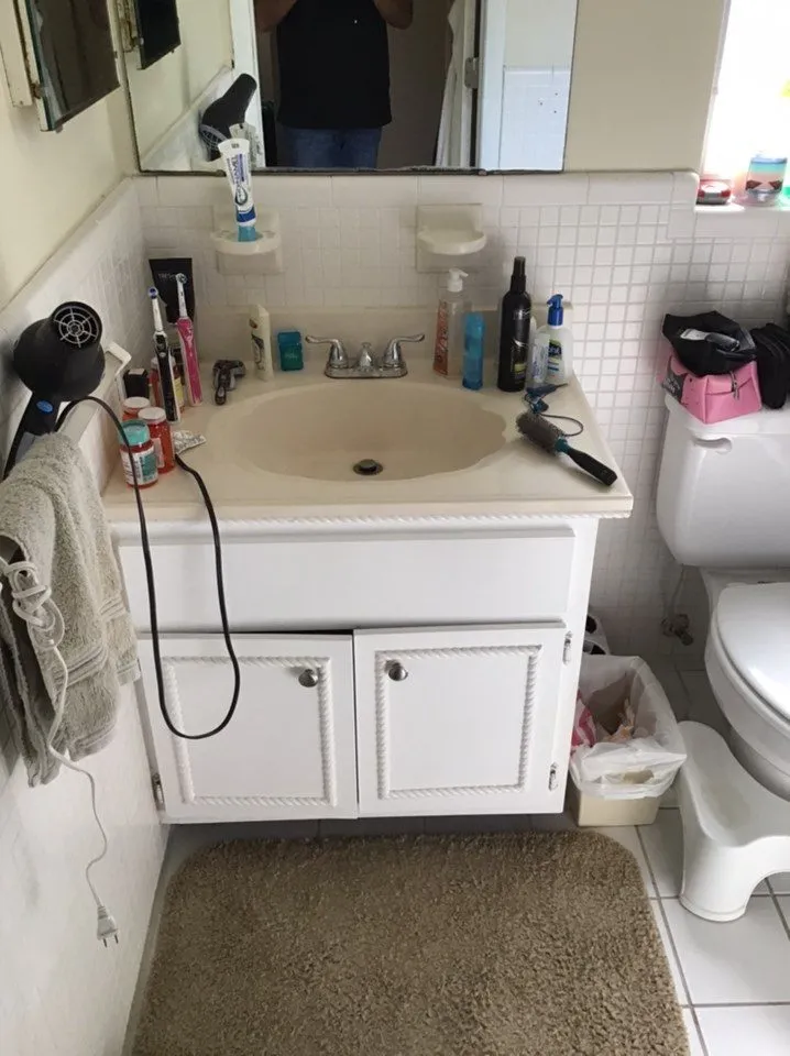 Bathroom before remodeling in Sarasota with cramped single vanity, dated cultured marble top, and square tile wainscot