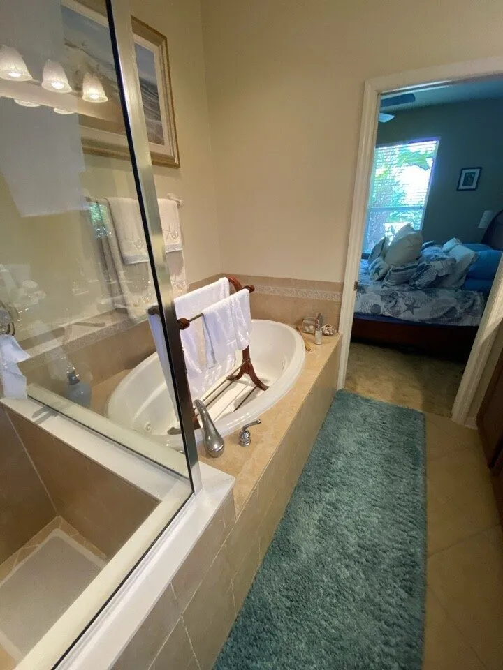 Dated Tampa primary bathroom before remodeling with garden tub and framed glass shower