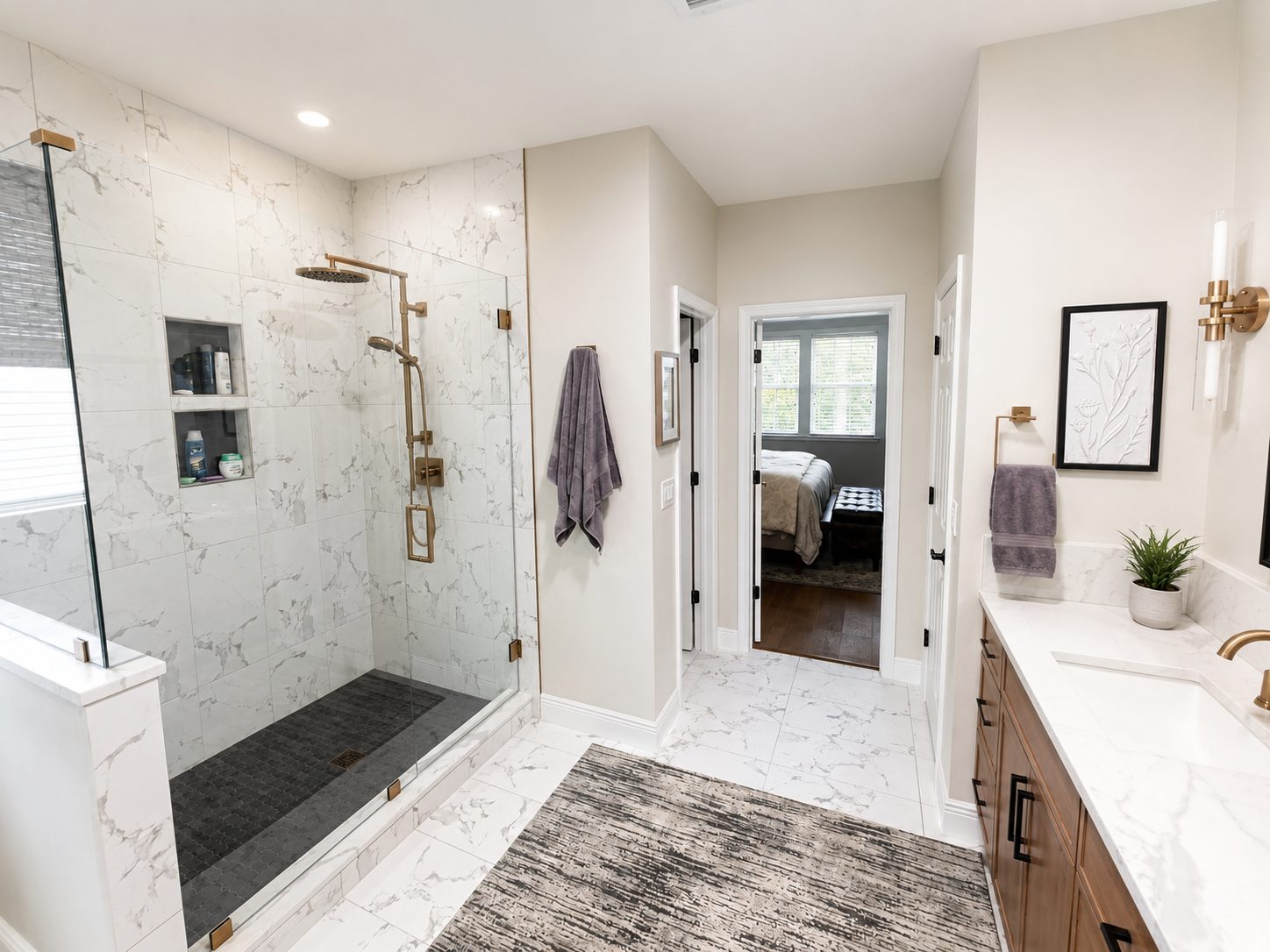 Master bathroom with marble look shower walls, dark contrast shower pan, marble look floor tile, and warm metal fixtures in a Lakewood Ranch remodel