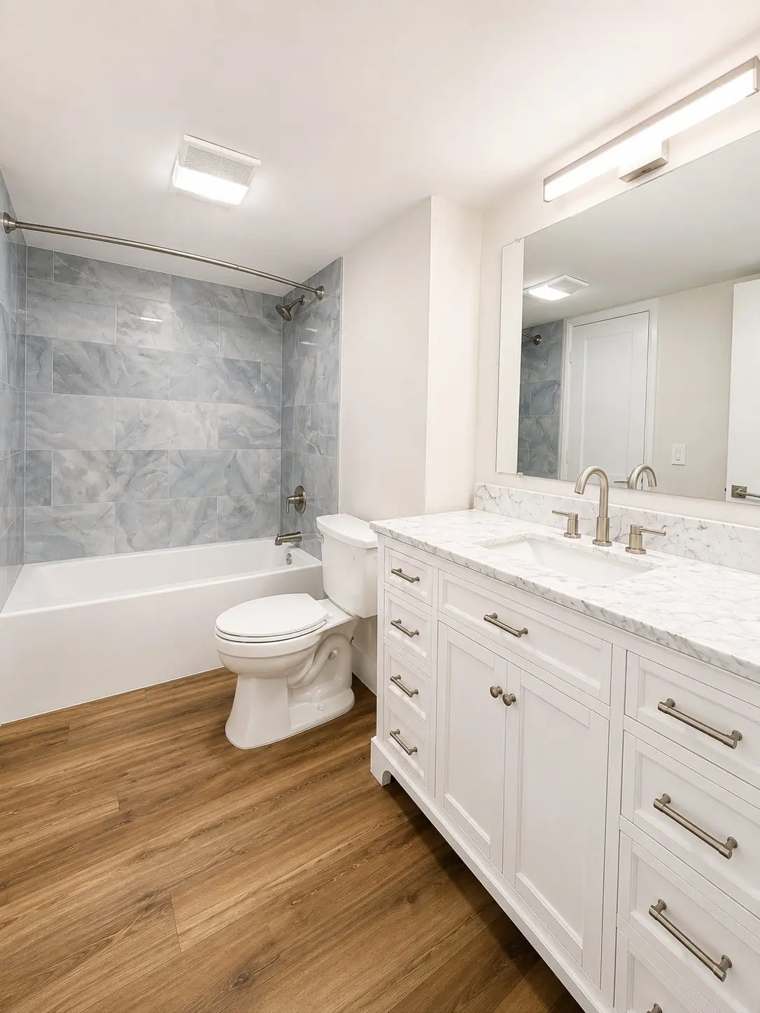 Tub and shower combination with blue gray stone look wall tile, white vanity, and marble countertop in a New Port Richey bathroom remodel