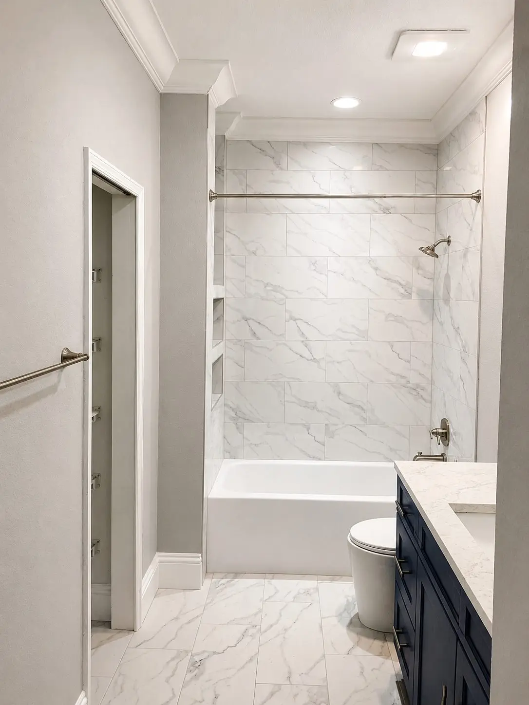 Guest bathroom with gray veined marble look tile on the tub surround and floor with stacked niches and a dark vanity in a Wesley Chapel remodel