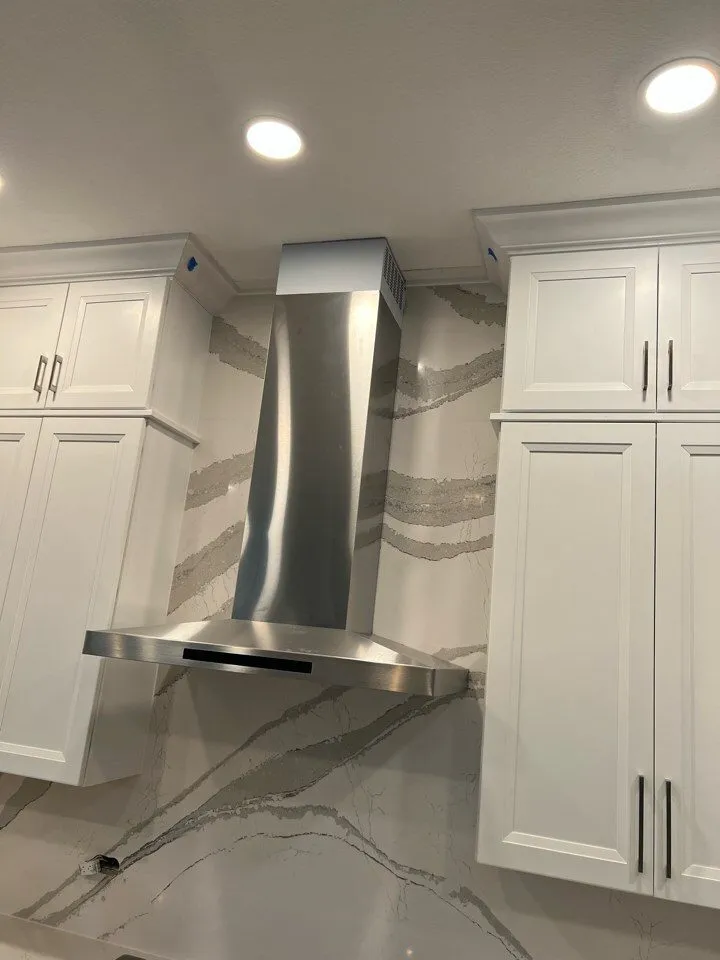 Cambria Brittanicca full height quartz backsplash behind a stainless range hood in a Siesta Key FL kitchen remodel
