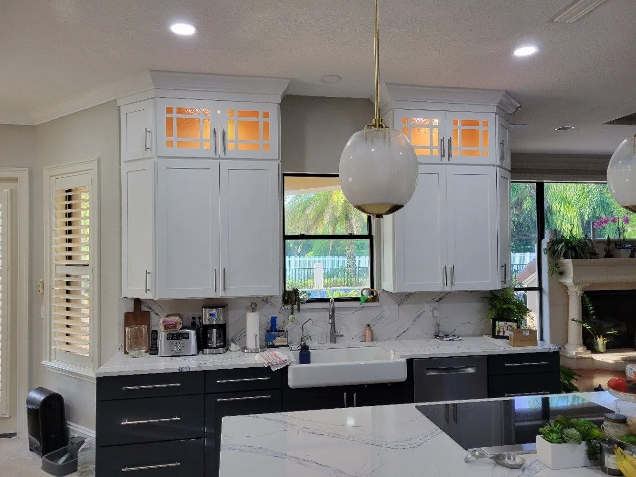 Cambria Portrush quartz kitchen island in an open Odessa FL kitchen with lighted glass upper cabinets and globe pendant