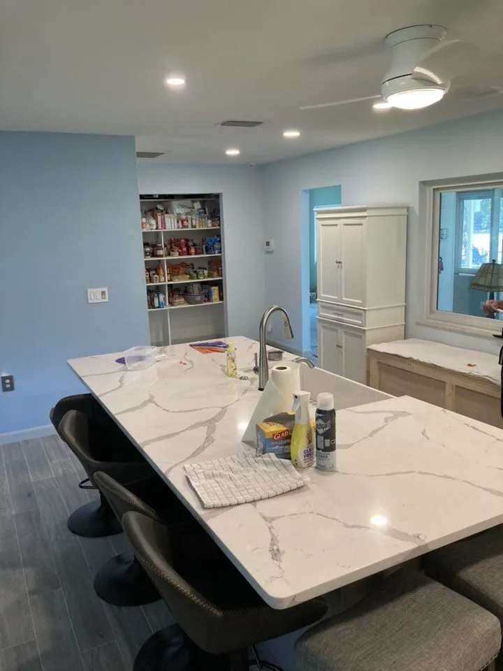 Long quartz kitchen island with seating and a prep faucet in a Land O Lakes FL kitchen remodel by CMK Construction