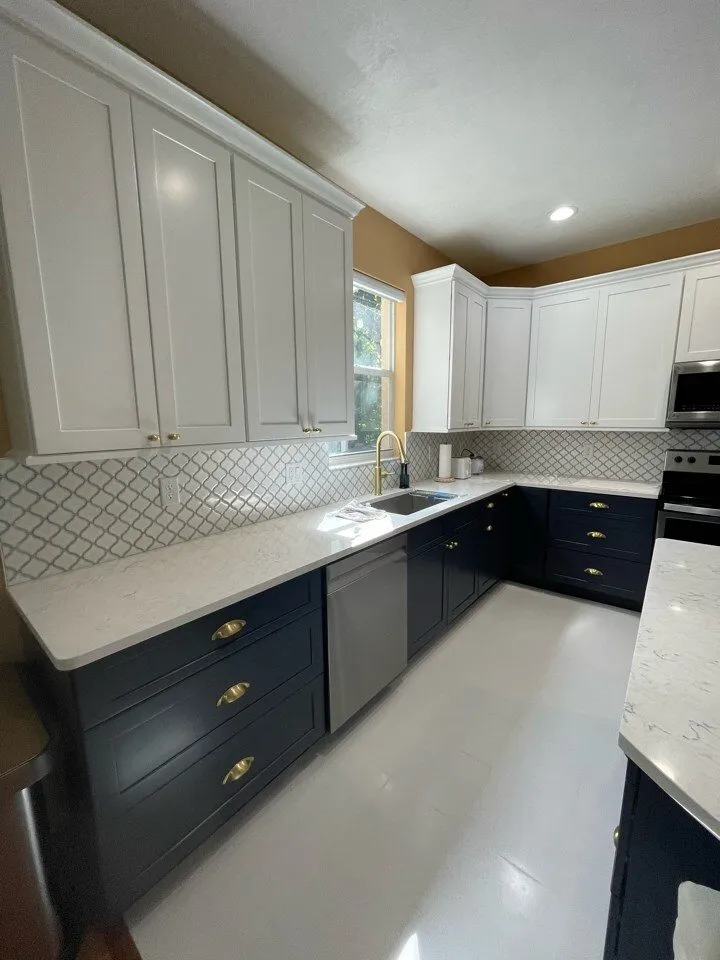 Two tone navy and white kitchen with Cambria Travella quartz countertops, brass hardware, and arabesque tile backsplash in Lutz FL