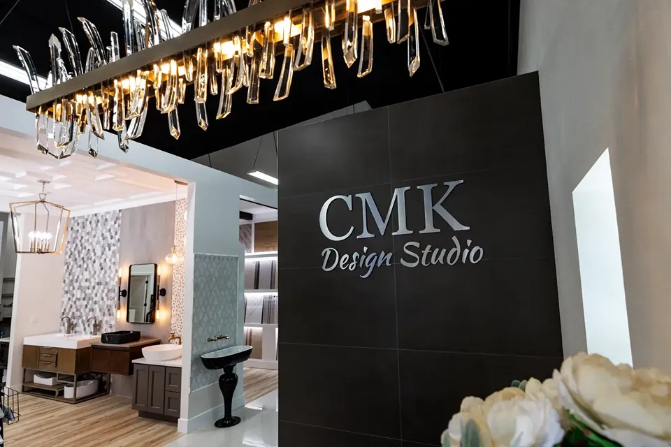 Interior of the CMK Design Studio in Tampa showing full bathroom vignettes, vanities, mosaic tile feature walls, and tile and slab sample displays