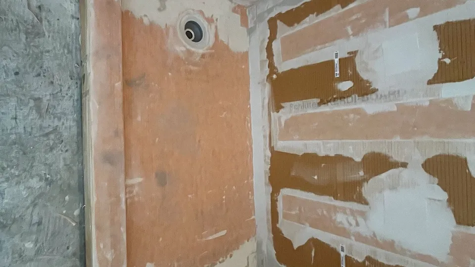 Actual CMK South Tampa bathroom project showing Schluter KERDI-BOARD with sealed seams and a shower pipe penetration before tile installation