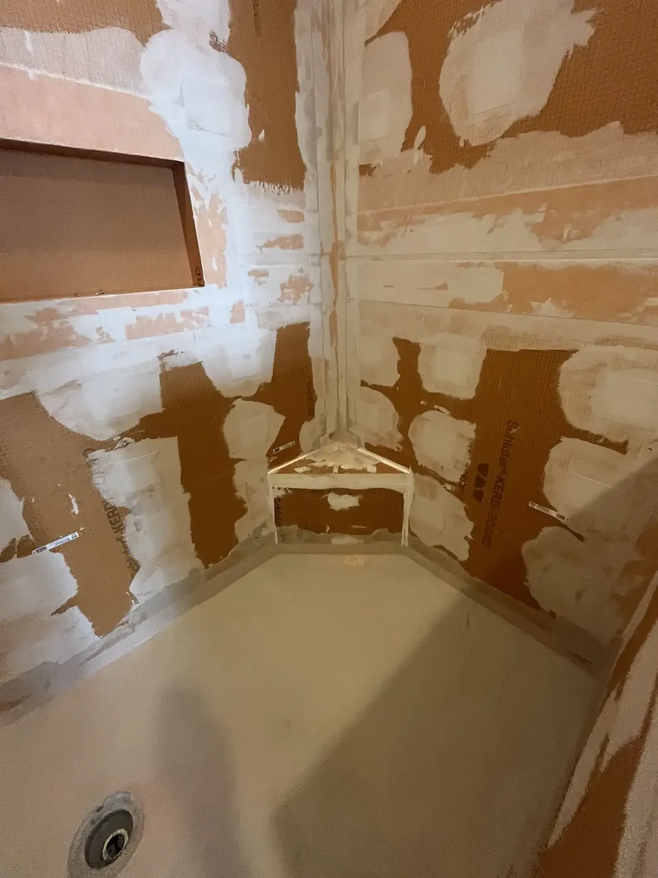 Actual CMK South Tampa shower project with Schluter KERDI-BOARD, banded seams, waterproofed corner bench, niche, and shower-floor assembly before tile