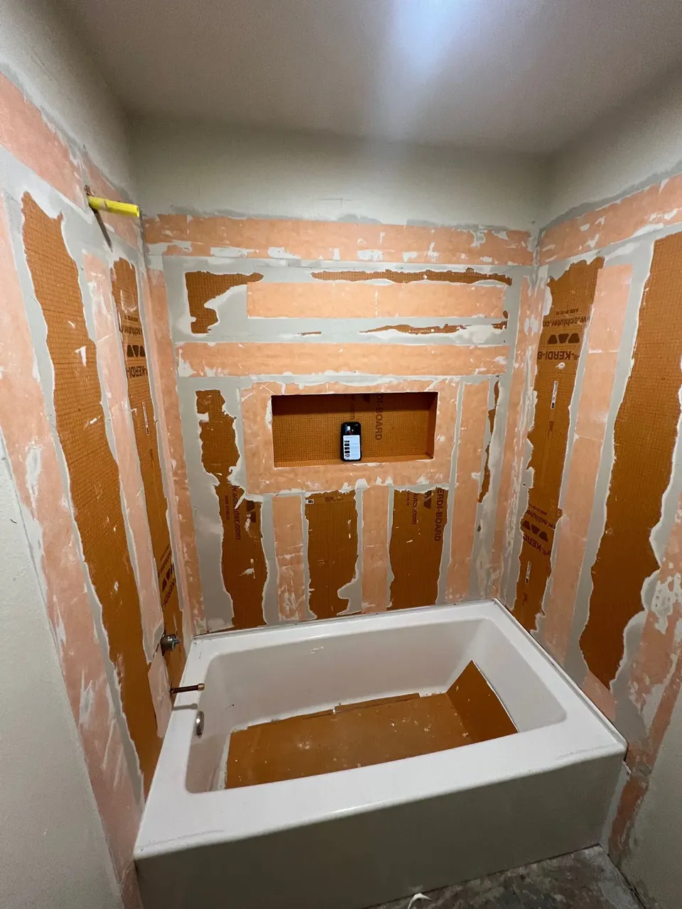 Actual CMK tub surround project showing Schluter KERDI-BOARD, sealed seams, plumbing penetrations, and a recessed niche before tile