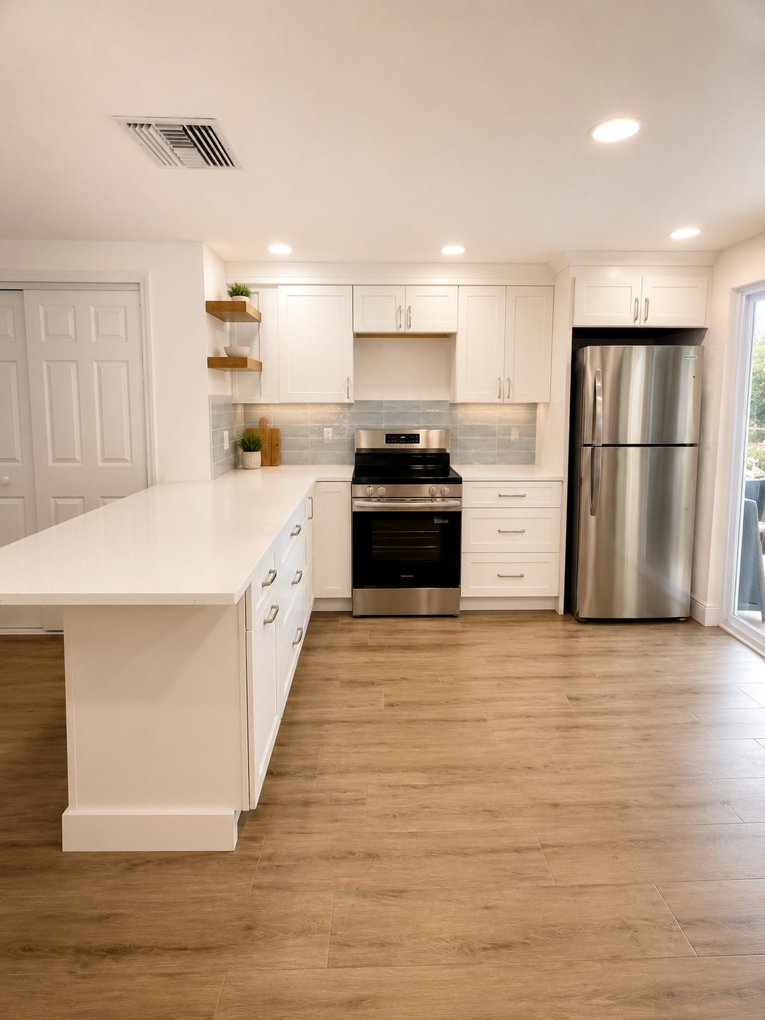 compact white kitchen with peninsula, pale blue backsplash, and floating shelves in lakewood ranch florida by cmk construction