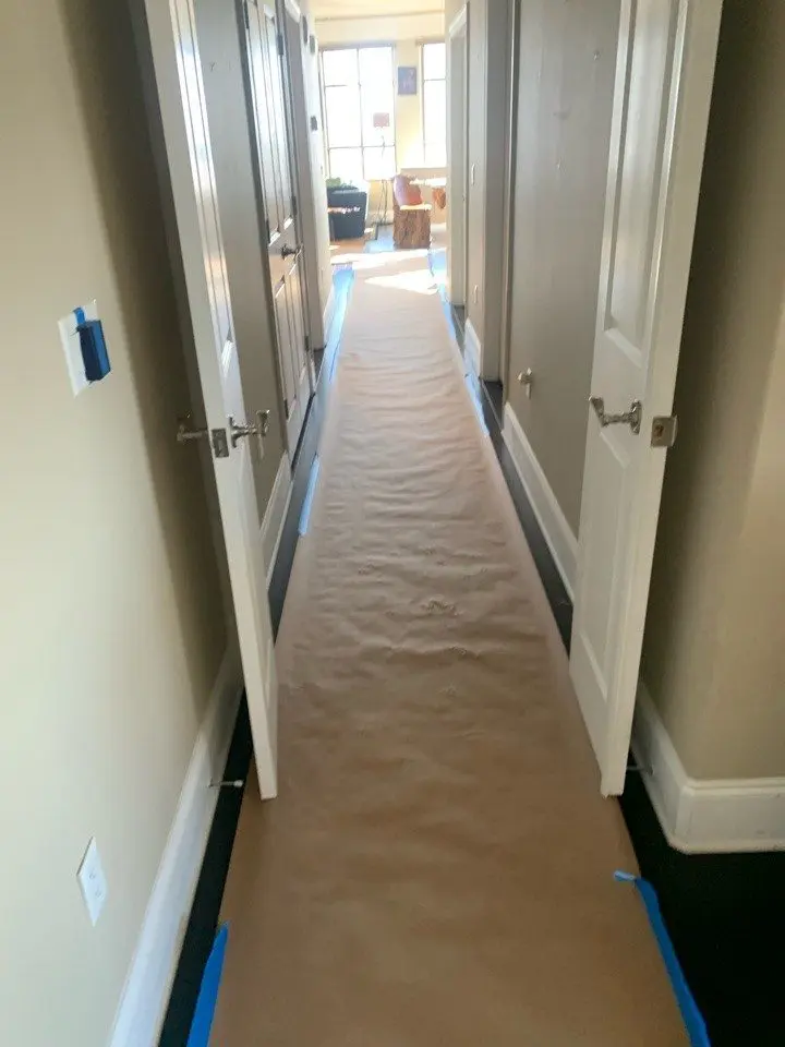 Full floor protection taped over hardwood flooring through a condo unit hallway during a CMK remodel