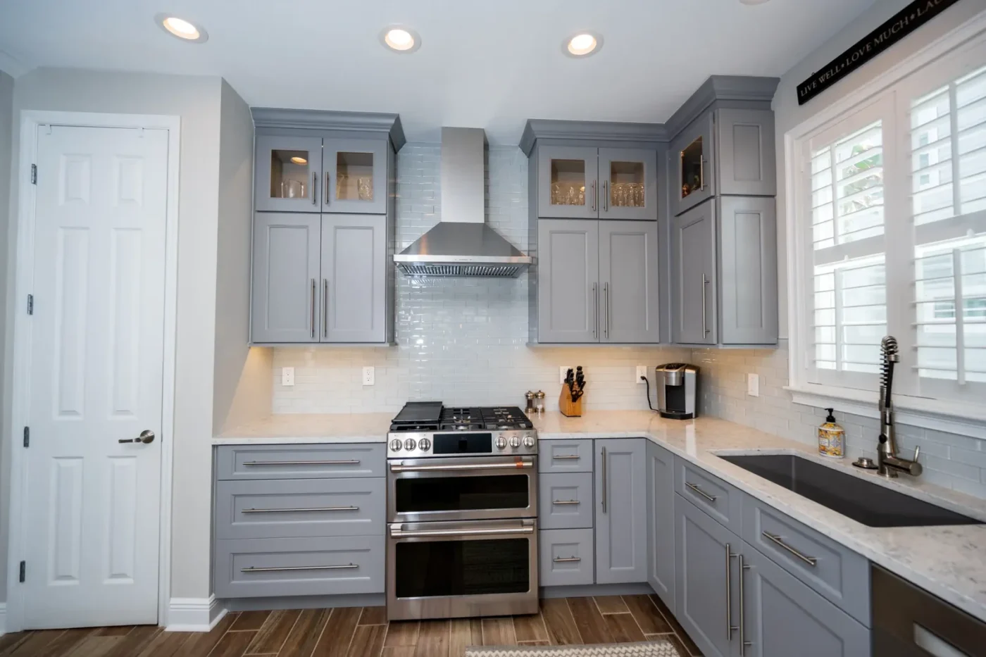 Tampa Bay kitchen with Fabuwood Allure Fusion cabinets in a cool grey paint, glass mullion uppers, stainless double oven range, and a glass subway tile backsplash by CMK Construction
