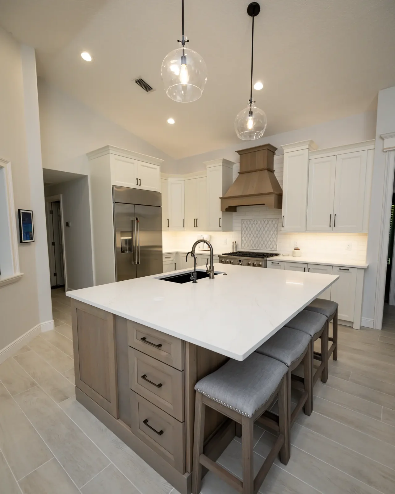 Clearwater Florida kitchen with a two tone Fabuwood Allure Fusion layout, warm off white perimeter cabinets, a stained island, a wood hood, and glass globe pendants by CMK Construction