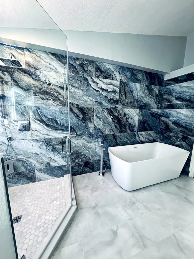 Modern bathroom featuring a white soaking tub set against striking blue and gray marble wall tiles.