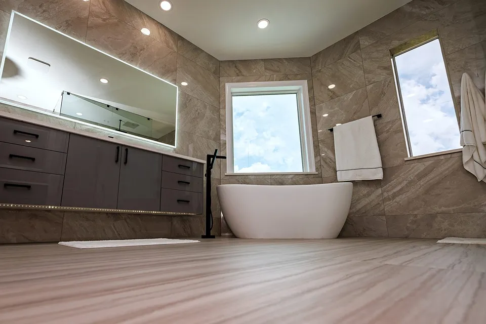 Modern egg-shaped freestanding soaking tub between two windows with a matte black floor-mounted filler and floating LED vanity in a Tampa owner's suite bathroom