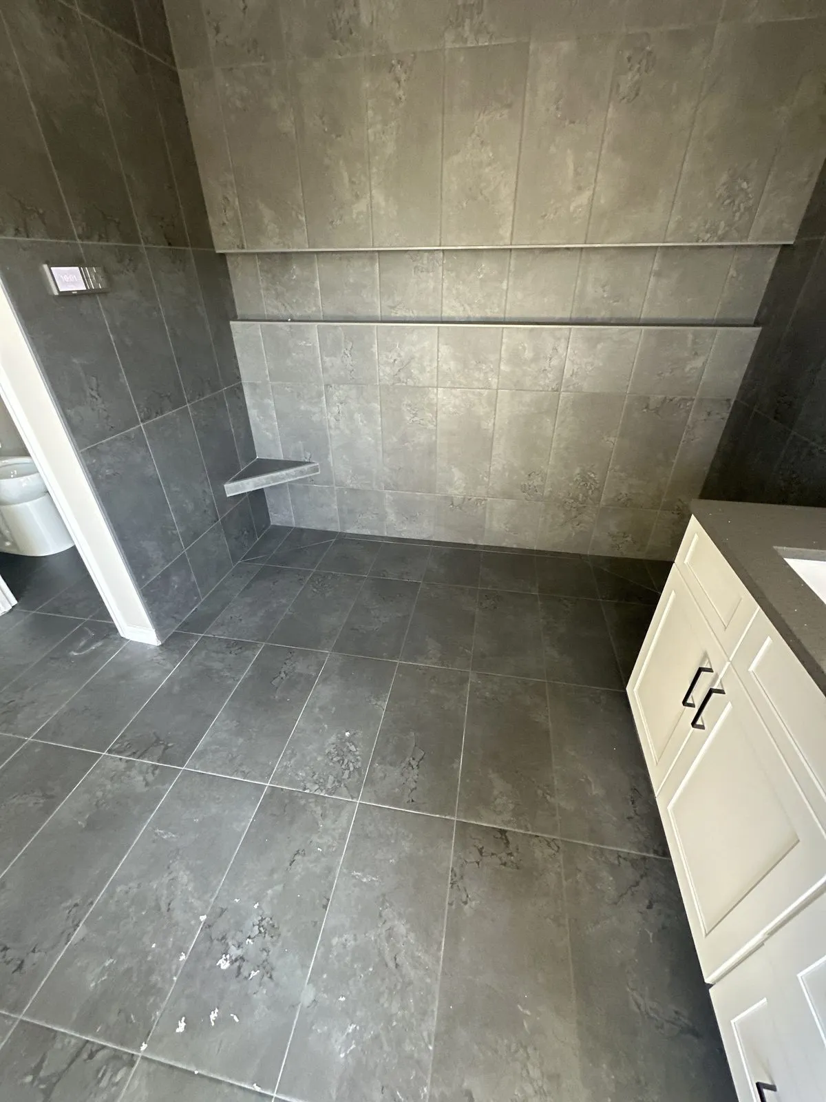Full width shower niche planned into the tile layout of a curbless South Tampa shower with corner bench by CMK