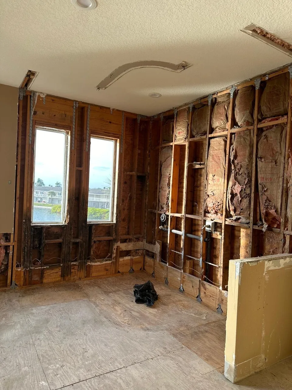 Bathroom gutted to the studs during demolition of a Tampa waterfront remodel with water damaged framing visible around the windows