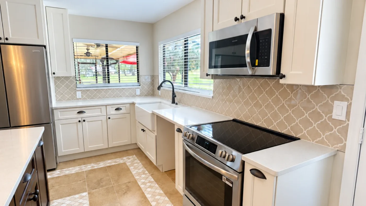 Finished Hudson kitchen sink and range wall with white shaker cabinets, white quartz, an arabesque backsplash, and a stainless range