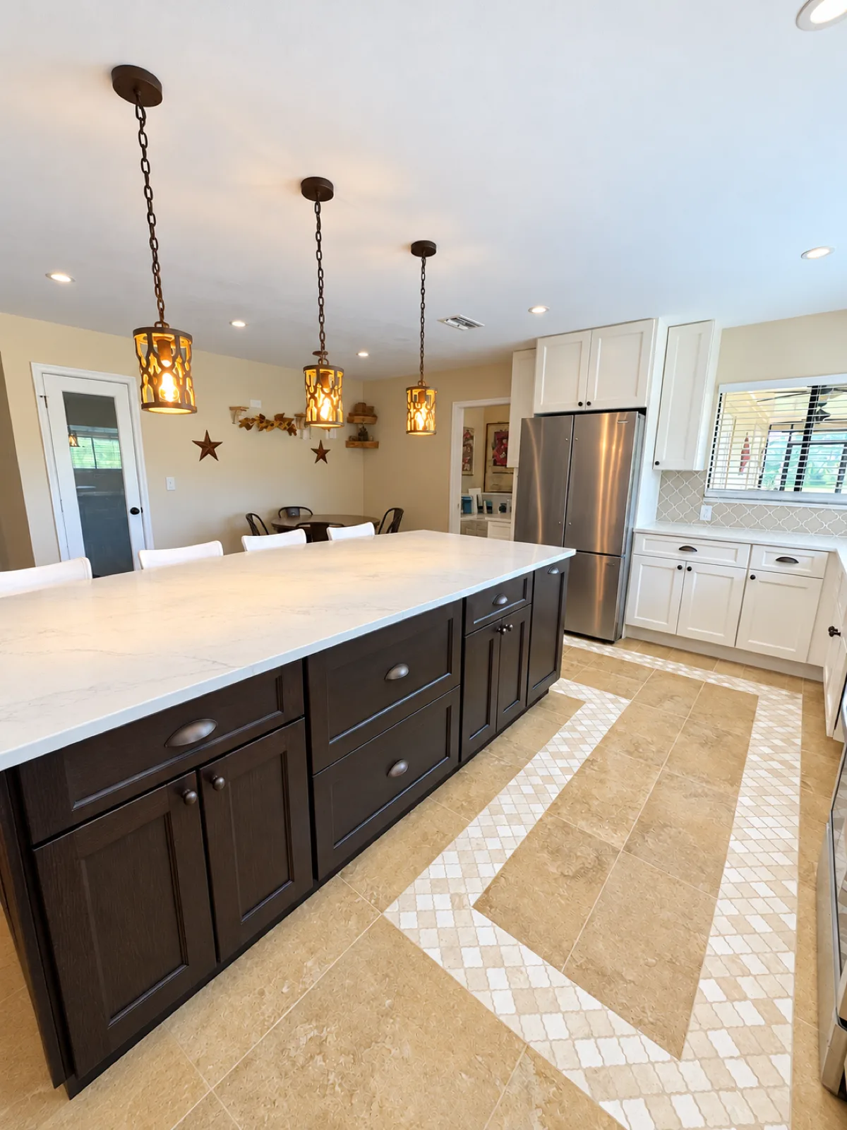 Finished Hudson kitchen island with three pendant lights, the refrigerator wall, and the mosaic tile border on the floor