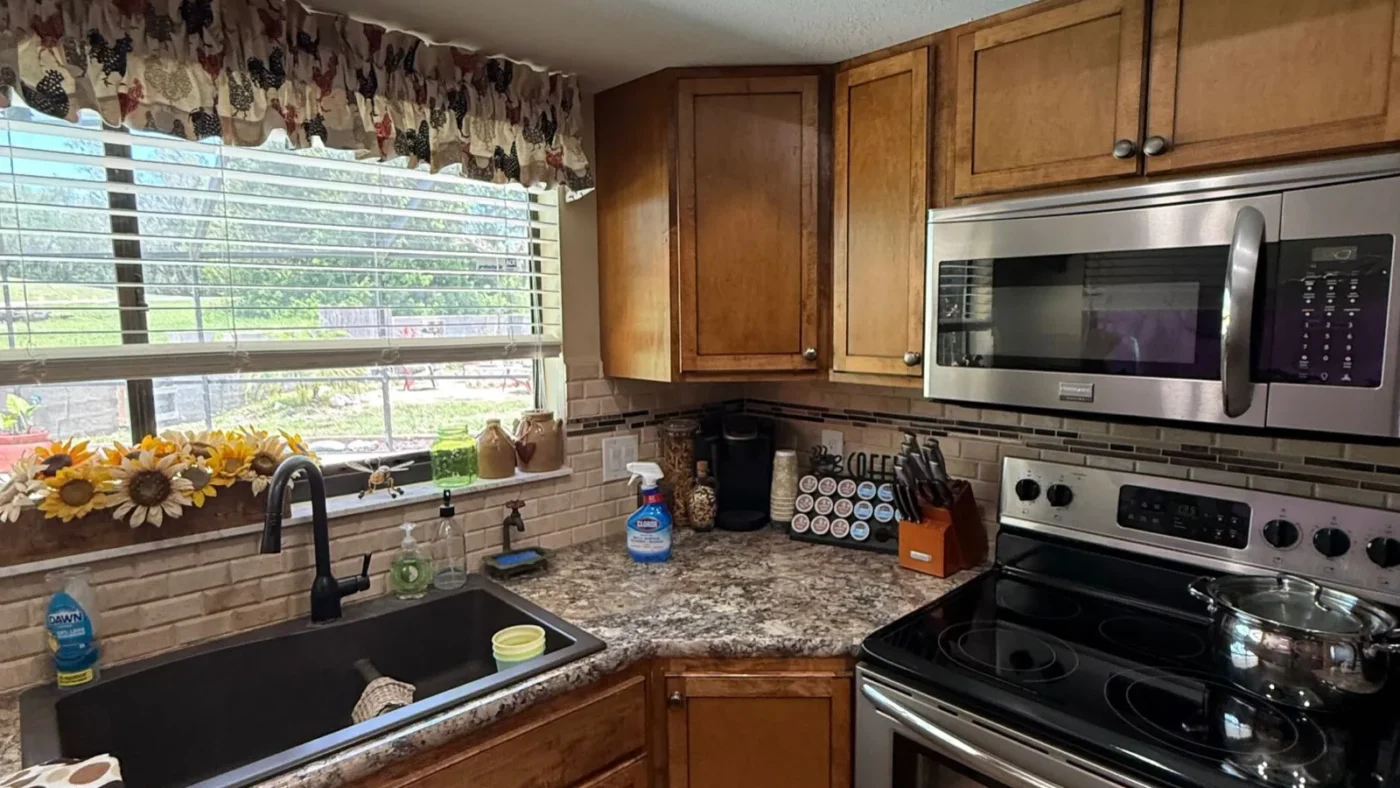 Before photo of the same Hudson kitchen with maple cabinets, laminate counters, and a dark sink in the corner