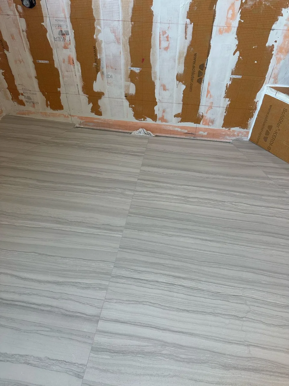Schluter Kerdi membrane with sealed seams and a linear drain on shower walls before tile in a Tampa master bathroom remodel