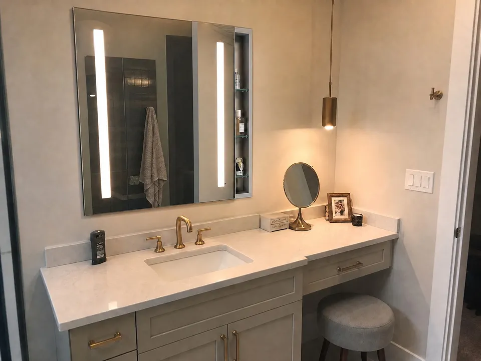 Lighted LED medicine cabinet and aged brass pendant over a makeup vanity, a storage and lighting idea for Brandon bathrooms