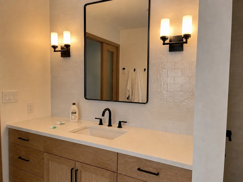 Matte black vanity lighting sconces with warm LED bulbs over a white oak vanity, a coastal modern idea for Sarasota bathrooms