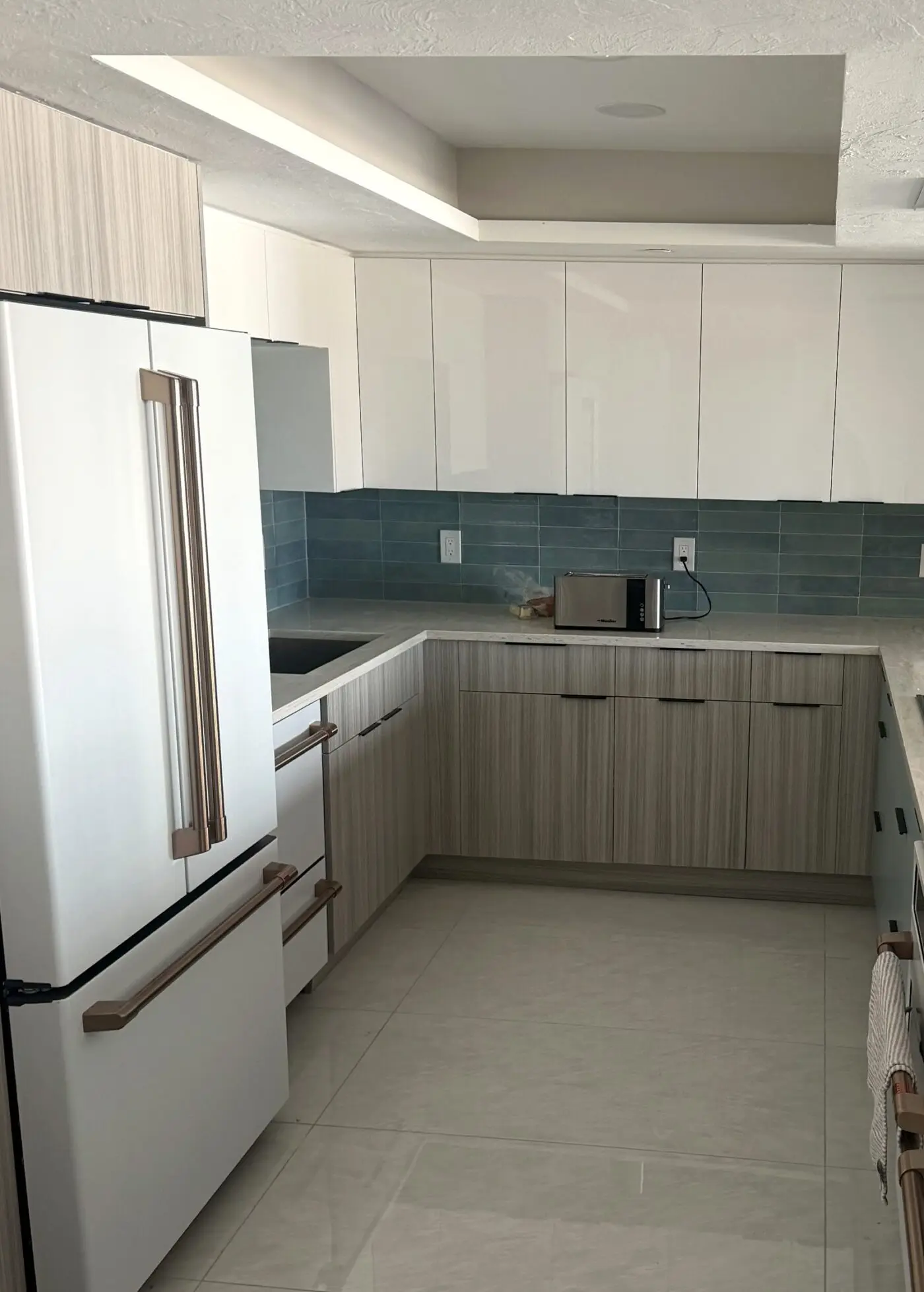 modern two tone kitchen cabinets with white gloss uppers and woodgrain lower cabinets and teal tile backsplash in a Land O Lakes Florida remodel by CMK Construction