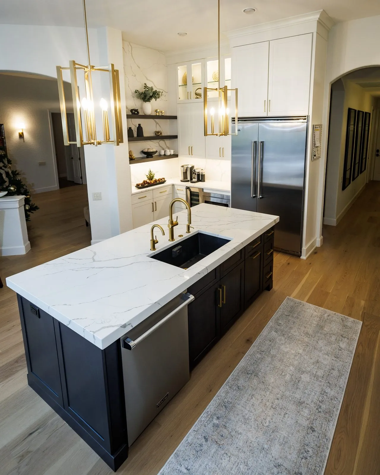 Black kitchen island with MSI Calacatta Laza quartz countertop, black workstation sink, and brass faucets in a Palm Harbor FL remodel
