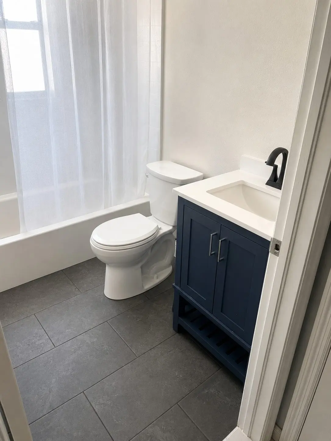 Navy blue small bathroom vanity with open shelf and white top in a Clearwater bathroom remodel