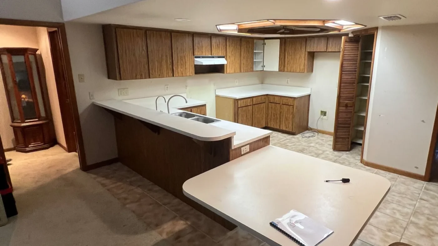 Before photo of the same Odessa kitchen with 1980s laminate cabinets and a tall peninsula knee wall